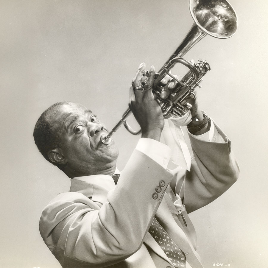 An iconic studio photo of Louis Armstrong playing the trumpet