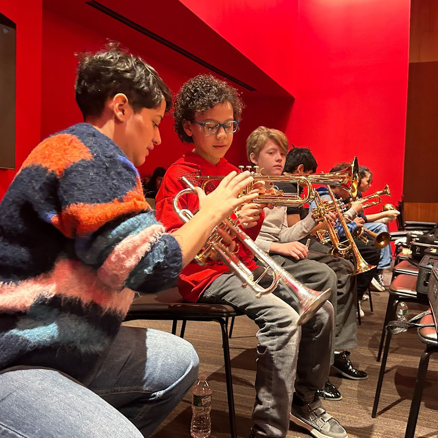 A trumpet lessons instructor helping students in the Louis Armstrong House Museum's Trumpet Learning Program